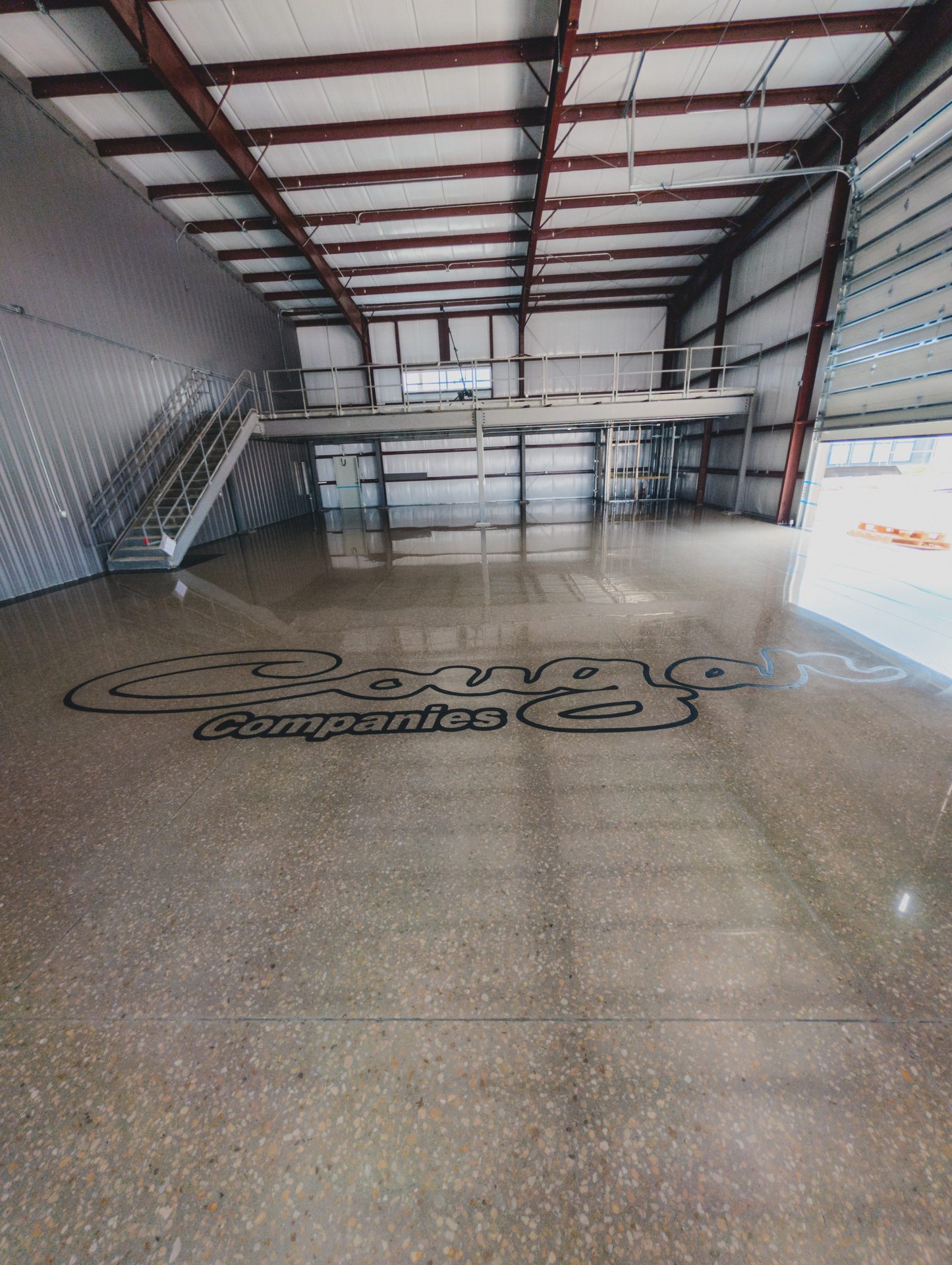 Finished Cougar Companies warehouse with full aggregate polished concrete and 24-foot engraved logo